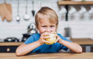 Мальчик кушает яблоко