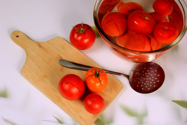 a lot of blanched tomatoes in a bowl with water ready for peeling - Лечо двухцветное с душистыми травами
