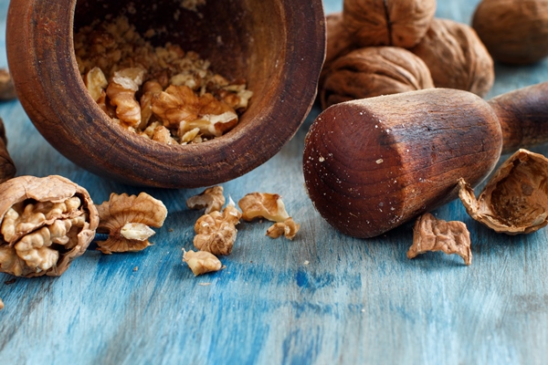 fresh walnuts with mortar and pestle on a blue wooden table close up - Медовая коврижка