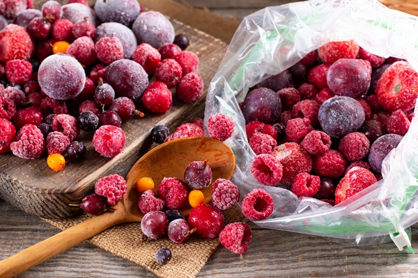 frozen berries on a cutting board on a wooden table frozen food food storage - Фрукты, ягоды