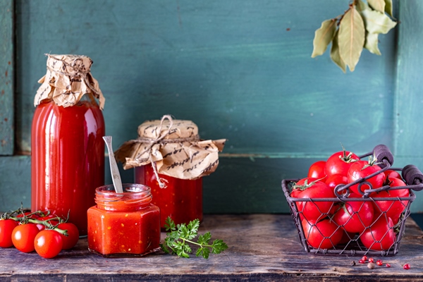 homemade tomato ketchup made from ripe red tomatoes in glass jars with ingredients on an old wooden table - Венгерское лечо
