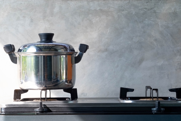 iron pot on a black gas stove on a kitchen grey cement blur for background macro - Русский хлебный суп