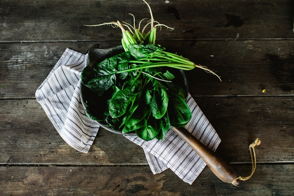 overhead shot of a bunch of spinach and a towel on an old wooden table - Как лучше сохранить продукты?