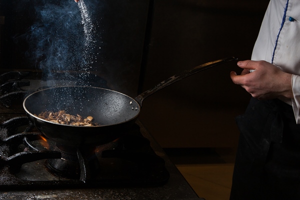 side view mushroom frying with salt and fire and human hand in pan - Русский хлебный суп