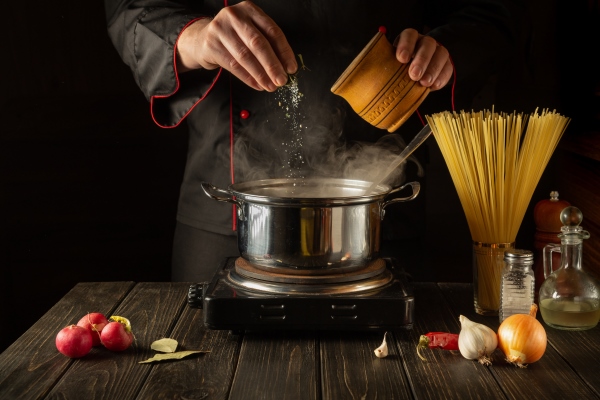 the chef adds salt to stock pot of boiling water - Крупяные и макаронные изделия: полезные советы