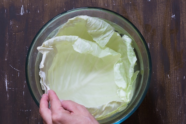 top view of cabbage leaves in hot water before stuffing on the brown background - Постные голубцы