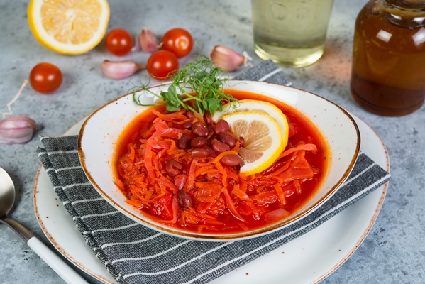 ukrainian vegetarian borscht with red beans in a white plate stands on a gray concrete background - Постный борщ с фасолью