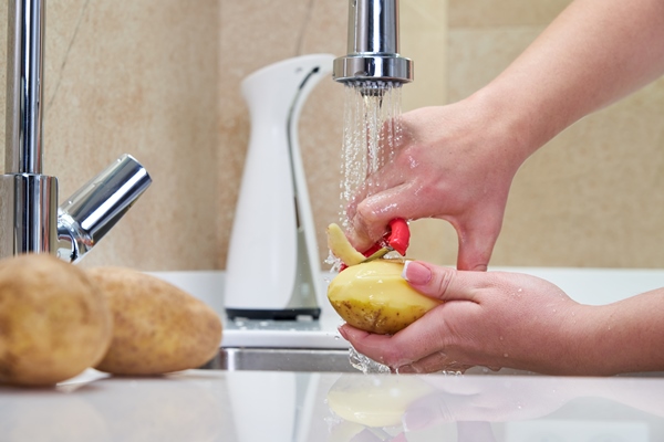 woman peeling potatoes over a sink - Постный гороховый суп