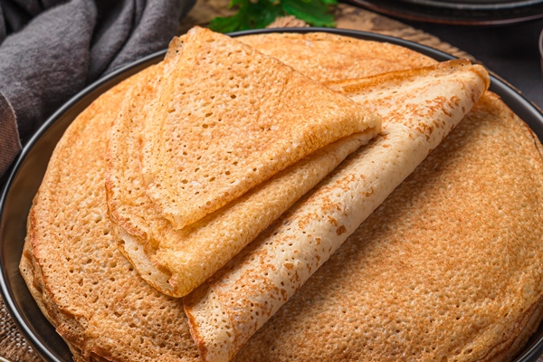 a stack of fried pancakes on a dark background maslenitsa traditional russian blini top view vertical - Постные блинчики с капустой и баклажанами
