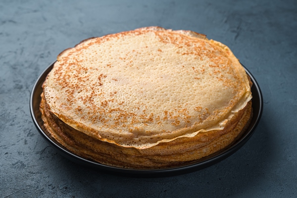 a stack of traditional fried thin pancakes on a dark gray blue background maslenitsa russian blini top view - Постные гречнево-картофельные блины