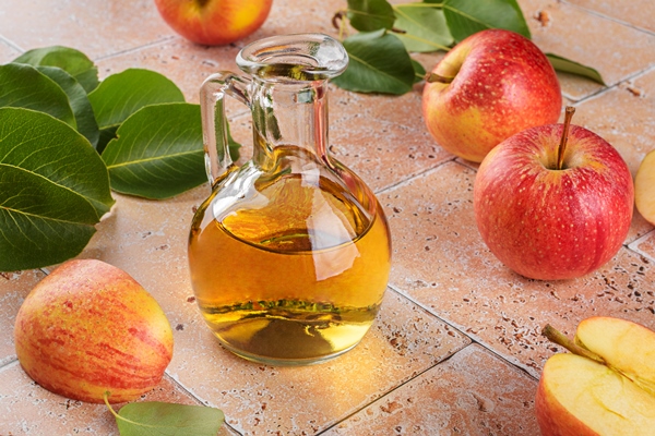 apple cider vinegar of fermented fruit in glass bottle with apples on beige travertine tiles table background - Тыква в сладком маринаде