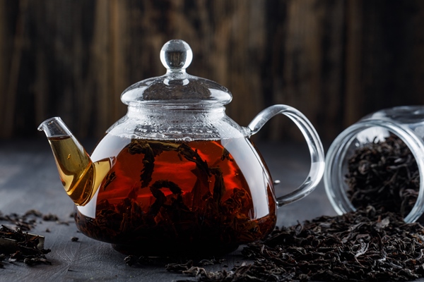 black tea with dry tea in a teapot on wooden surface side view - Постные блинчики на чае с пряной начинкой