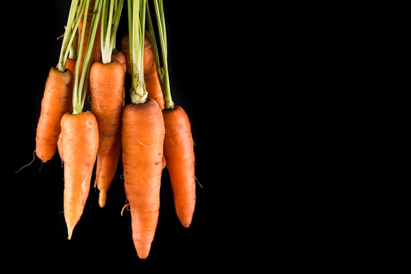 carrots on black background with copy space - Постные блинчики со сладкой морковью и изюмом