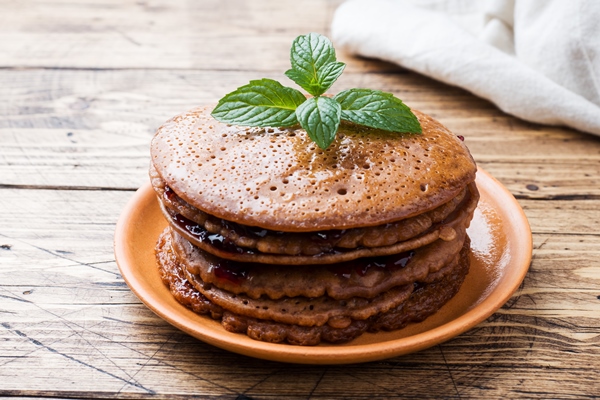 chocolate pancakes with berry jam and mint for breakfast on wooden table - Постные блинцы с какао