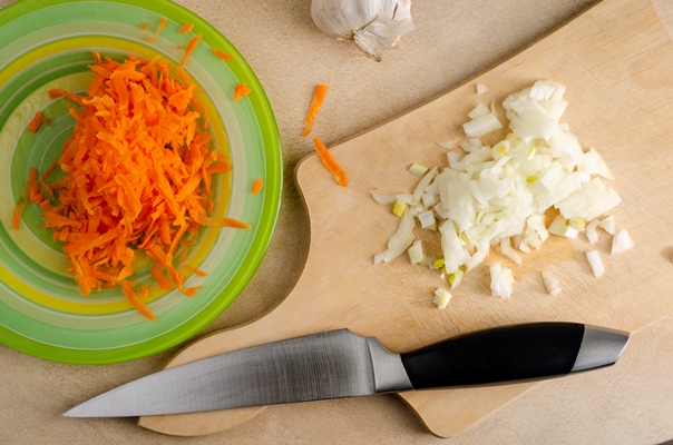 chopped onion on a wooden cutting board and grated carrot on the plate and knife - Монастырская кухня: луковые котлеты, пшенная каша