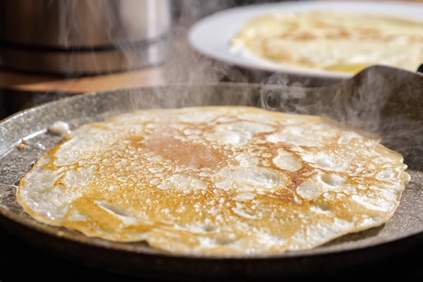 close up of frying pancake in a pan - Постные рисово-кокосовые блинцы
