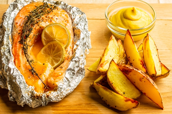 close up of the fresh baked fish in foil wit thyme and small amount of friend potatoes with mustard near - Красная рыба, запечённая в фольге