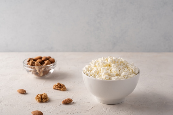cottage cheese in a bowl and almonds on a light background - Пасха с какао, миндалём и изюмом