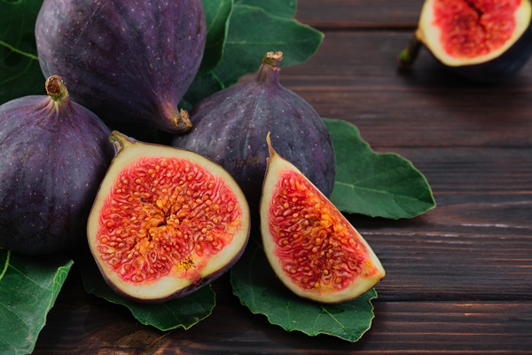 figs and halves of several fruits closeup on the leaves of a fig tree on an old wooden table horizontal frame seasonal fruits fig harvest background or mediterranean diet articles - Библия о пище