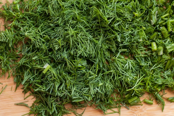 finely chopped fresh dill on a wooden cutting board with blurred edges - Русские гречневые дрожжевые блины