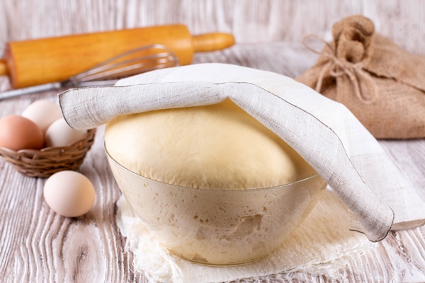 fresh yeast dough for pizza bread baguettes sourdough on wooden table yeast dough in a glass bowl - Пао-де-Деус