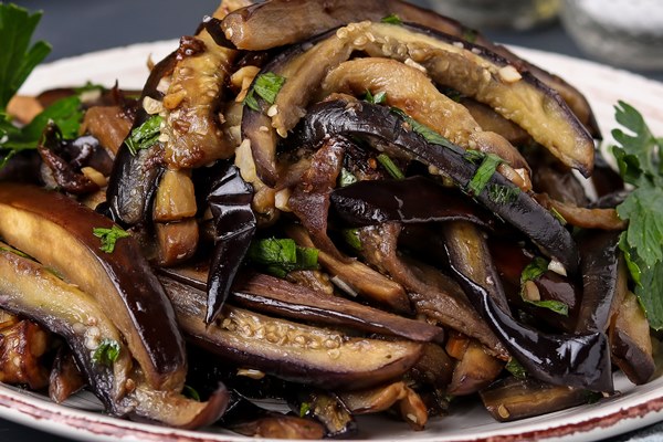 fried eggplants with garlic and soy sauce sliced in stripes in a plate against a dark - Хе из баклажанов и капусты на зиму (без стерилизации)