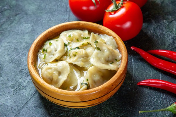 front view yummy meat dumplings inside wooden plate with fresh tomatoes on dark surface - Пельмени с судаком