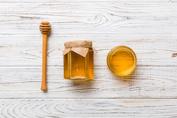 glass jar of honey with wooden drizzler on colored background honey pot and dipper high above top view copy space - Имбирный лимонад