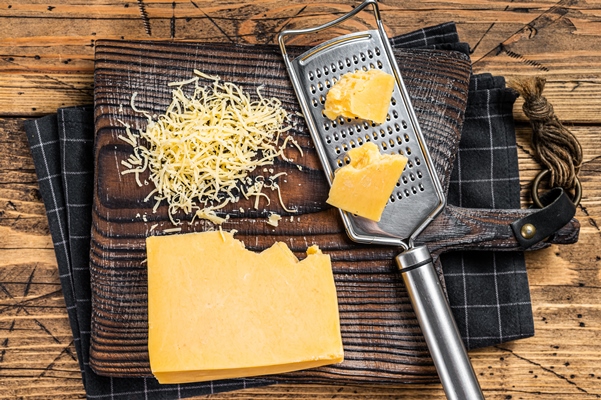 grated cheddar cheese piece on a wooden board wooden background top view - Рыбная запеканка с рисом