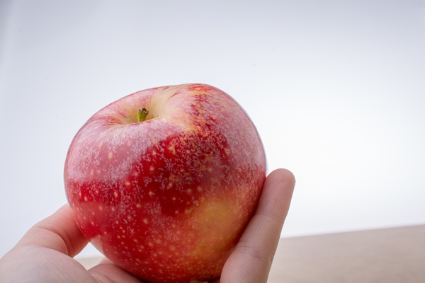 hand holding a red apple on wood - Творожное суфле