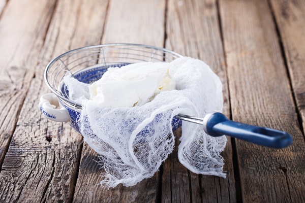 homemade cottage cheese in a cheesecloth and sieve - Пасха с изюмом