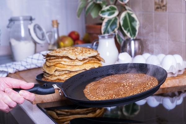 housewife woman bakes pancakes for breakfast home cooking pancakes in pan on glassceramic stove in her kitchen diy ingredients for making pancakes selective focus 2 - Постные блинчики со свёклой и орешками