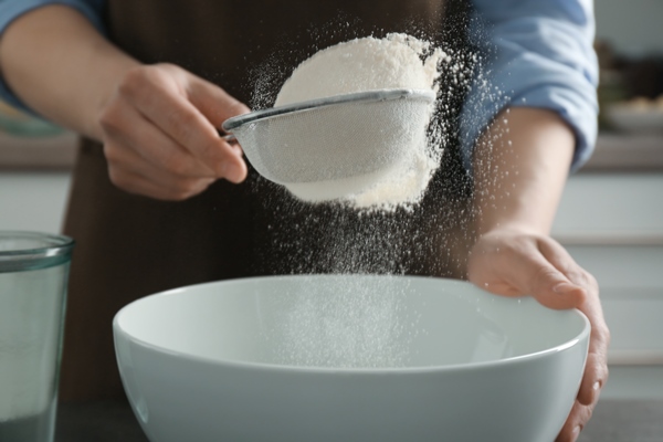 human hands sifting flour into ceramic bowl closeup - Постные блины кислые на картофельном отваре