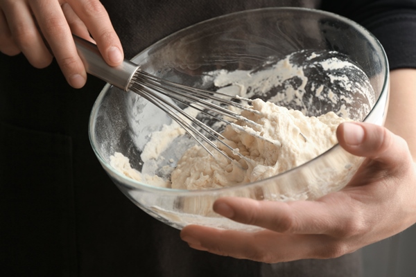 human hands stirring dough with flour in glass bowl - Постные блинчики со свёклой и авокадо