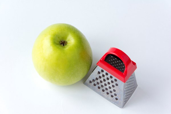 juicy ripe green apple and a small grater isolated on a white background - Салат из перца с яблоком