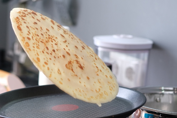 male chef tossing pancake in frying pan in kitchen closeup - Постные яблочные блинцы на соевом молоке