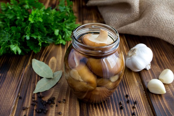 marinated mushrooms shiitake in the glass jar on the brown rustic wooden surface - Грибы натуральные консервированные