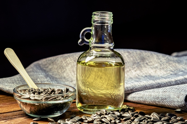 organic sunflower oil in a small glass jar close up photo of sunflower oil with seeds on a wooden background the concept of a bio and organic product - Постные блинчики с яблоками