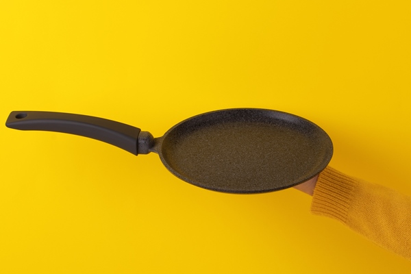 pancake pan utensil on hand over yellow background - Постные банановые блинцы на минеральной воде