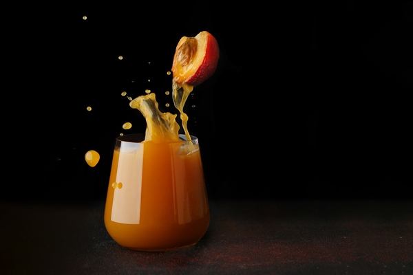 peach or apricot juice pouring in glass half of fruit levitation splash of juice into glass juice concept on dark background - Постные заварные блинчики с ягодным соусом
