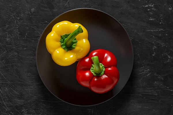 peppers two bulgarian sweet yellow and red on gray plate top view dark background with space to copy - Салат из перца с огурцами