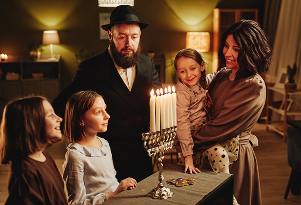 portrait of modern jewish family looking at silver menorah candle during hanukkah celebration in coz - Библия о пище