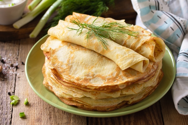 potato pancakes not sweet served with garlic cream sauce on rustic wooden table - Постные картофельные блинцы