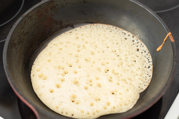 process of frying homemade pancakes on frying pan close up with selective focus - Постные гречнево-картофельные блины