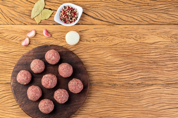 raw meat balls over wooden board with seasonings and copy space - Диетический куриный суп с гречкой и грибами