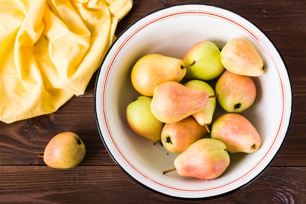 ripe pears in an enamel plate on a wooden table - Целые груши в сиропе