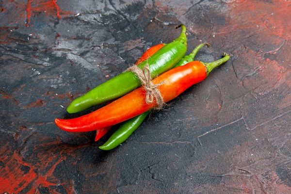 side view of cayenne peppers in different colors and sizes tied in one another with rope on mixed color table - Салат из перца с яблоком