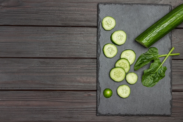 sliced green cucumber on black cutting board wooden background flat lay copy space - Ботвинья с рыбой постная старинная
