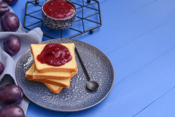 slices of bread with delicious homemade plum jam on wooden table - Пирожное из чернослива