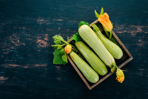 squash marrow zucchini in a wooden box on a black table top view copy space - Оладьи с кабачком